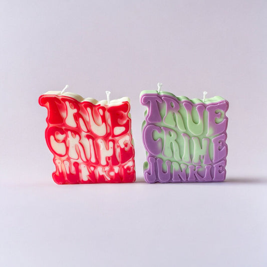 Une bougie true crime junkie rouge et blanche, et une bougie true crime junkie violette et vert