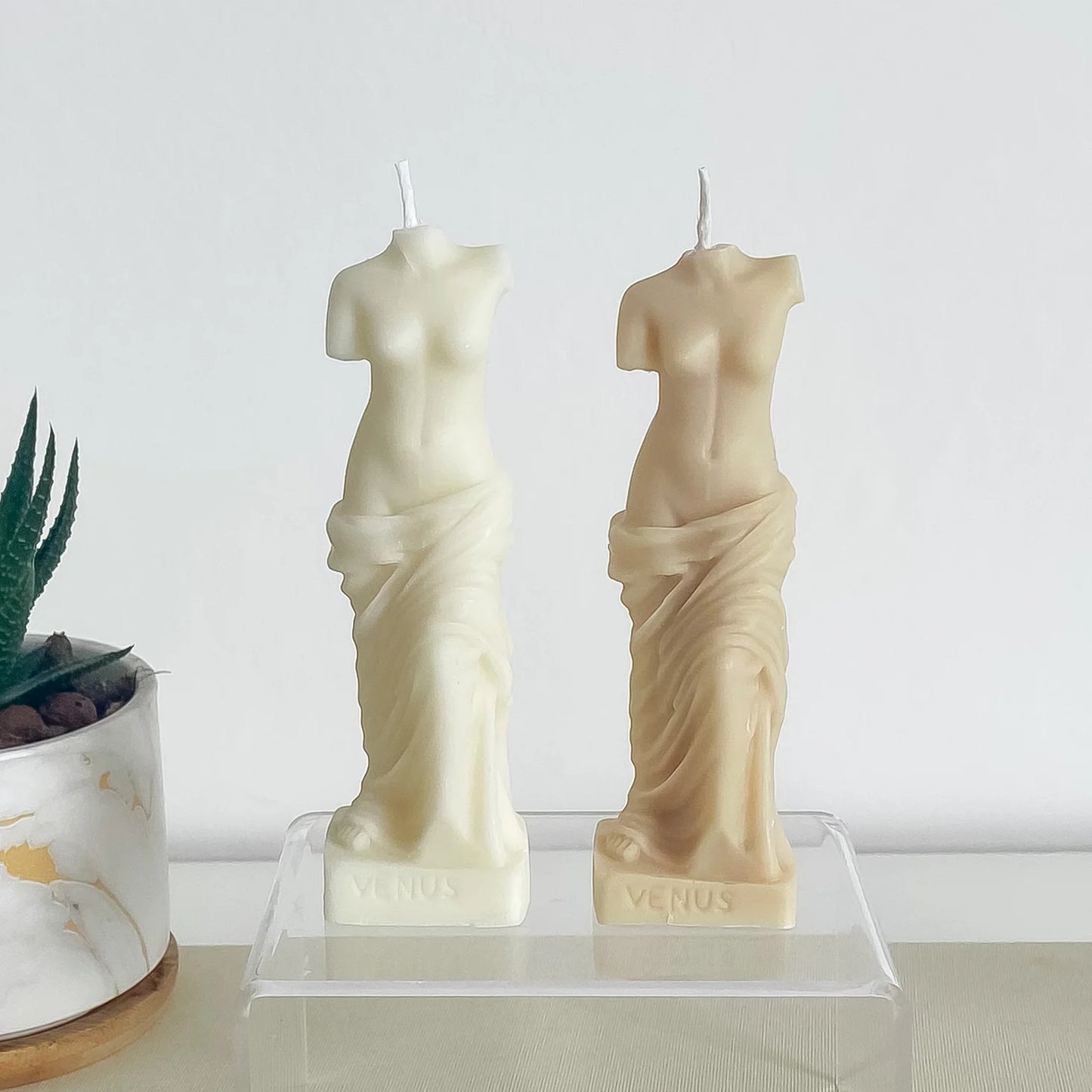 Une bougie blanche et une bougie beige, toutes deux formes en forme de buste de femme