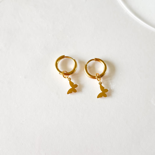 Deux charms papillon sur des boucles d'oreille plaquées or