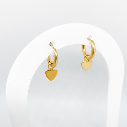 photo d'une paire de boucles d'oreille créoles plaquée avec petit coeur suspendu à un support design blanc