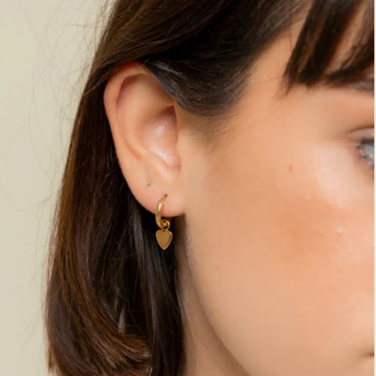 une boucle d'oreille créole plaquée or avec petit coeur portée par une femme