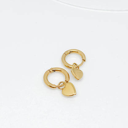 une paire de boucles d'oreille créoles plaquée or avec petit coeur accroché