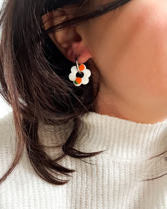 Photo d'une boucle d'oreille créole en forme de fleur avec motifs orange