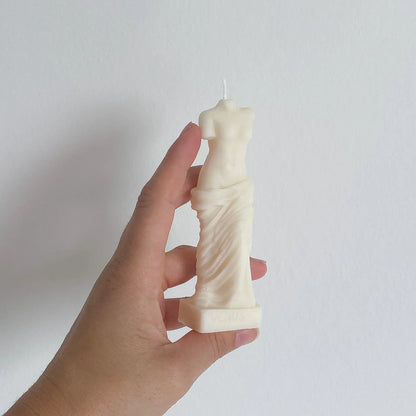 Une bougie blanche représentant un buste de femme, dans la main de sa créatrice