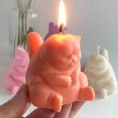 Photo d'une bougie chat grincheux allumée et de couleur orange. On voit d'autres modèles en arrière-plan, de différentes couleurs