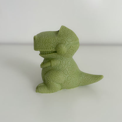 Photo d'une bougie en forme de dinosaure (T-Rex) verte, de profil