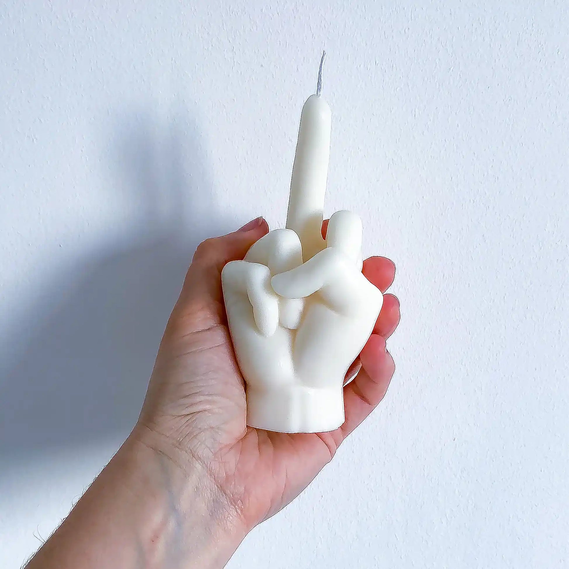 Une bougie fuck blanche, dans la main de la créatrice de la marque Gigi Pop