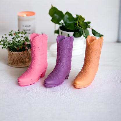 Un assortiment de bougies santiags de différentes couleurs (rose, violet, orange)