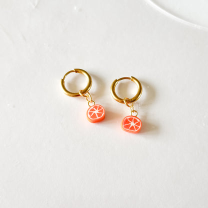 Photo d'un charm tranche d'orange accroché à une créole plaquée or