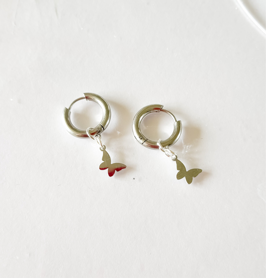 Deux charms papillon sur des boucles d'oreille plaquées argent