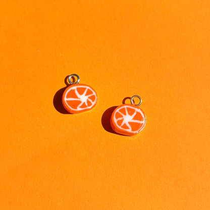 Photo de deux charms en forme de tranche d'orange, sur fond orange