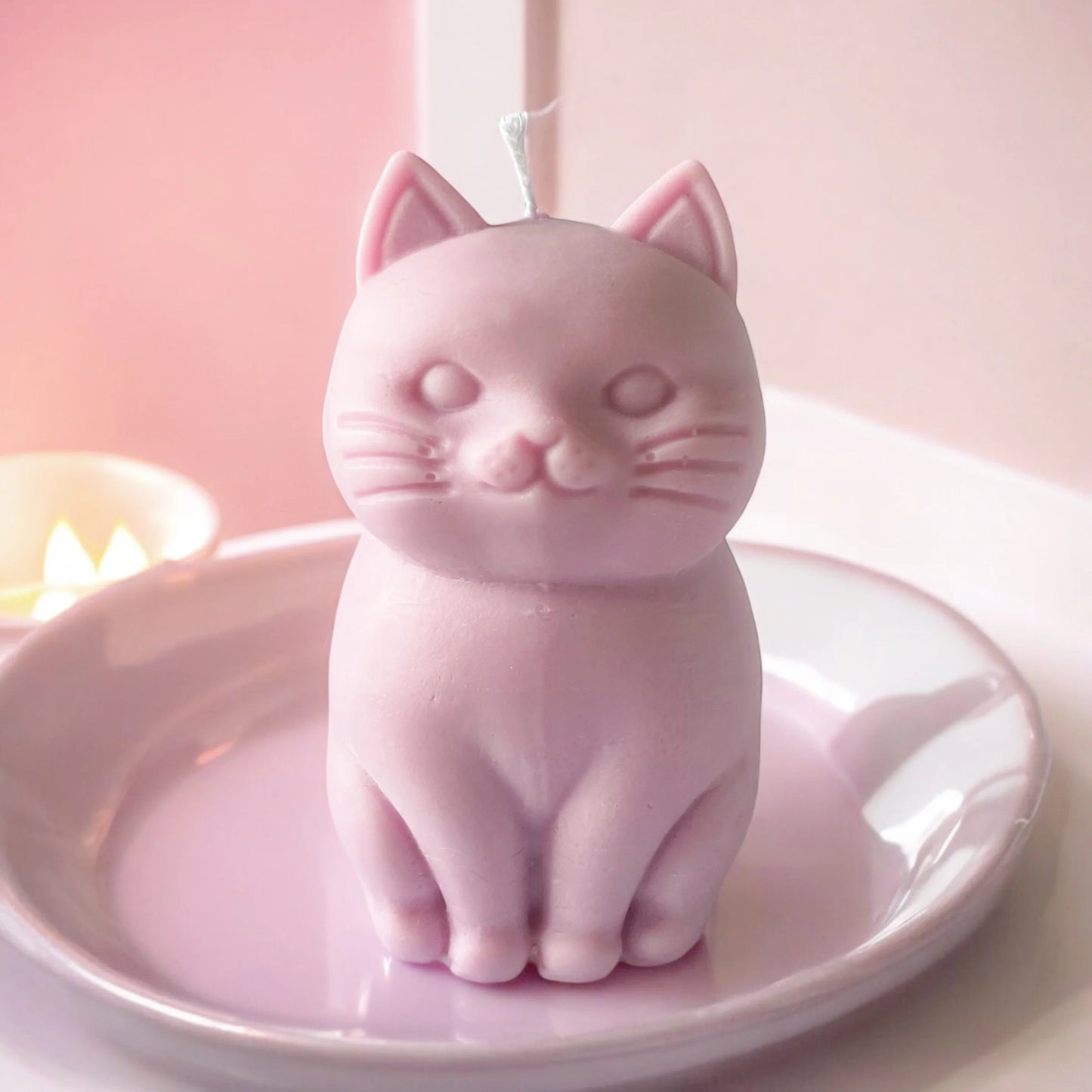 photo d'une bougie chat rose posée dans une assiette de la même couleur